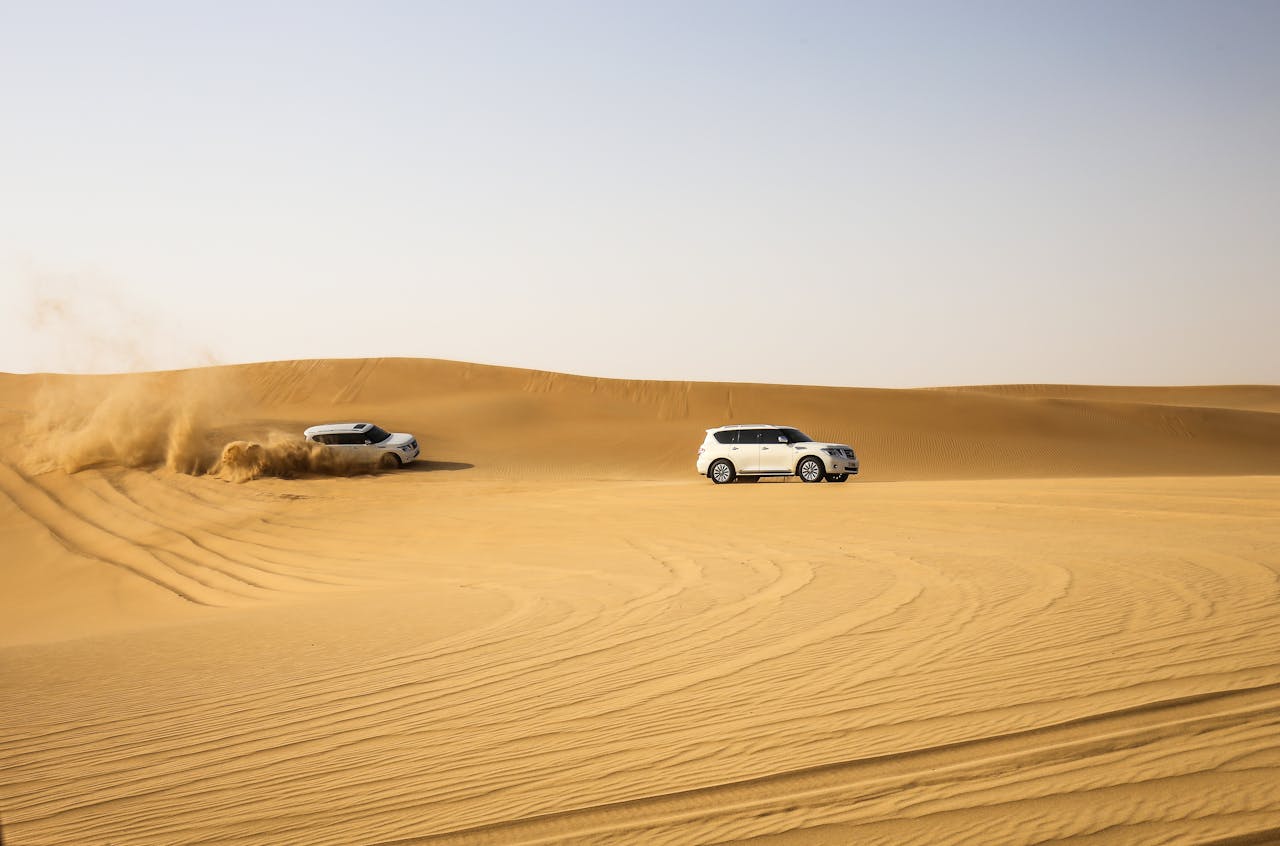 Two SUVs driving through the dunes in Abu Dhabi desert, capturing thrilling adventure moments.